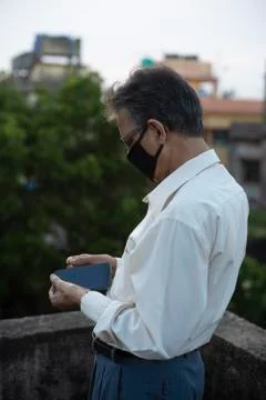Senior man with corona preventive mask removing the back cover of his cellpho Stock Photos