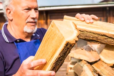 Senior man in defocused background put the wood ready to heat and warm home i Stock-Fotos