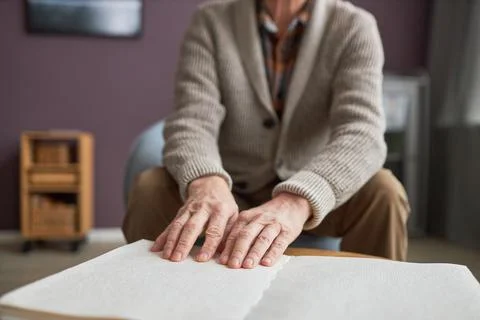 Senior man with disability reading a book in Braille Stock Photos