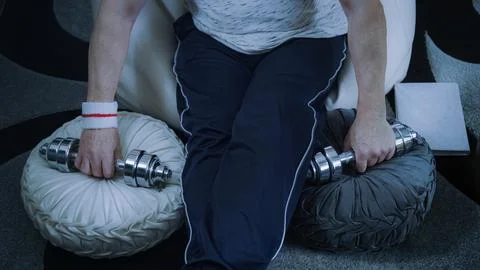 Senior man doing home workout with dumbbells, maintaining fitness in comfort Stock Photos