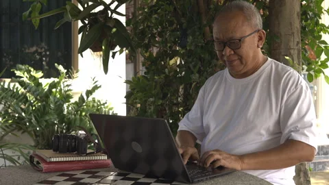 Senior man doing online work in the garden Stock Footage 253146873