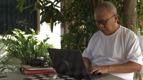 Senior man doing online work in the garden Stock Footage 253146907