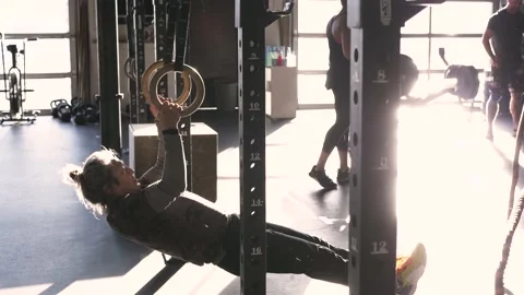 Senior man doing pull ups with rings in sunny gym Stock Footage 221040857