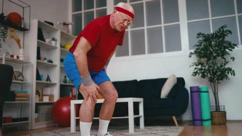 Senior man doing squats at home and feeling pain in his knee, sports injury Vidéo 247977103