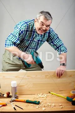 Senior man drilling plank in workshop Stock Photos