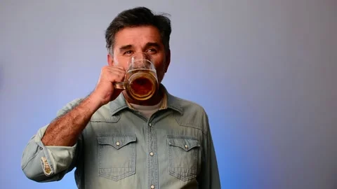 Senior man drinking beer, showing beer and smiling at camera. Video stock 148557852