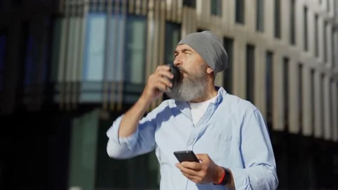 Senior man drinking coffee and using phone in street Video stock 135467259