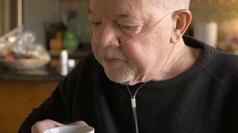 A senior man drinking coffee while wearing oxygen mask in slowmo Stock Footage 71722717
