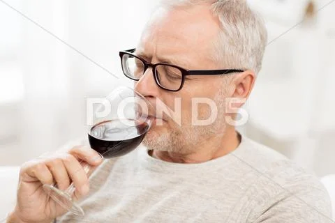 Senior man drinking red wine from glass at home Stock Photos
