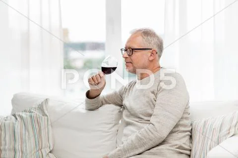 Senior man drinking red wine from glass at home Stock Photos