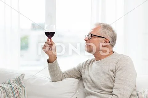 Senior man drinking red wine from glass at home Stock Photos