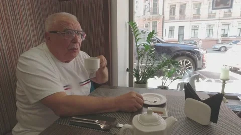 Senior man drinks tea waiting for dinner at table in cafe Stock Footage 140966885