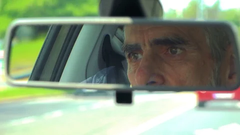 Senior man drives a car - reflection of his face in the rear view mirror Video stock 79156984