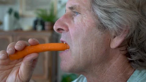 Senior man eating fresh raw carrot for healthy nutrition and wellness lifestyle Video stock 343727423