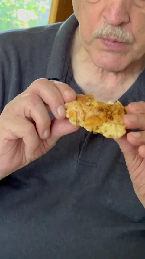 Senior man eats fried chicken thigh vertical view Stock Footage 219236800