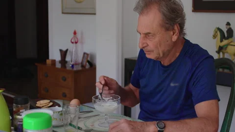 Senior man eats healthy breakfast at dining table at home, promoting balanc.. Stock Footage 340970283