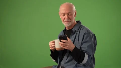 Senior Man Enjoying Coffee While Looking at Smartphone Against Green Screen Stock Footage 305998857