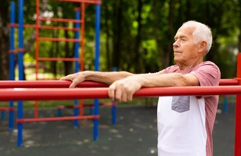 Senior man exercising at parallel bars outdoors Stock Photos