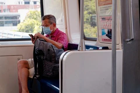 Senior Man with Face Mask Using Smartphone on Taipei MRT Priority Seat Fotos Stock