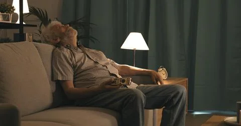 Senior man falling asleep while watching TV Stock Photos