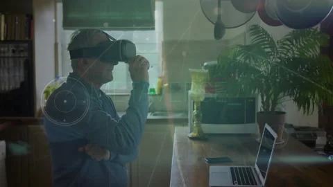 Senior man fitting VR headset at kitchen island, navigating metaverse with Stock Footage 311915899