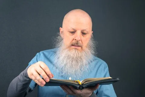 Senior man with a full gray beard passionately reading scripture from the b.. Stock Photos