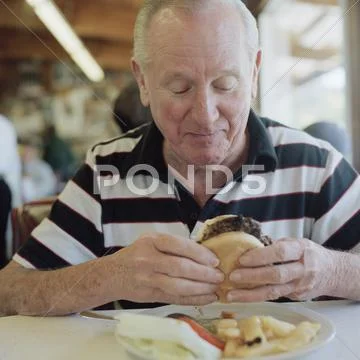 A senior man getting ready to eat a hamburger Stock Photos