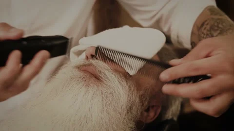 Senior man getting styling and trimming of his beard in the barbershop Stock Footage 233653284