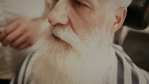 Senior man getting styling and trimming of his beard in the barbershop Stock Footage 233653588