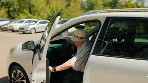 Senior man getting into a white car in the outdoor parking lot. Stock Footage 343264065