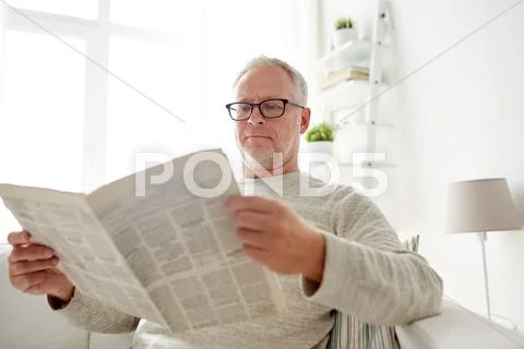 Senior man in glasses reading newspaper at home Stock Photos