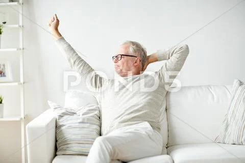 Senior man in glasses relaxing on sofa Stock Photos