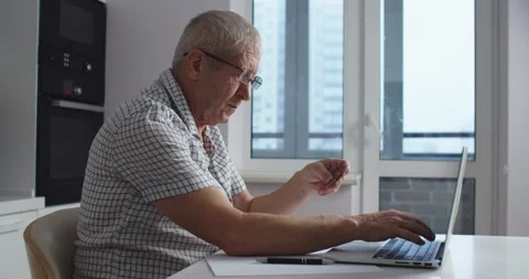 Senior man with glasses using laptop computer does shopping online and paying Stock Footage 146884675