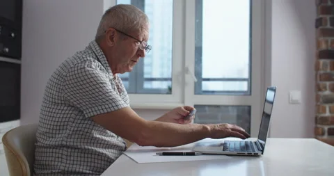 Senior man with glasses using laptop computer does shopping online and paying Stock Footage 147151898