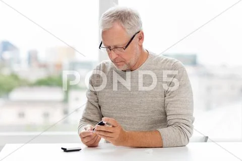 Senior man with glucometer checking blood sugar Stock Photos
