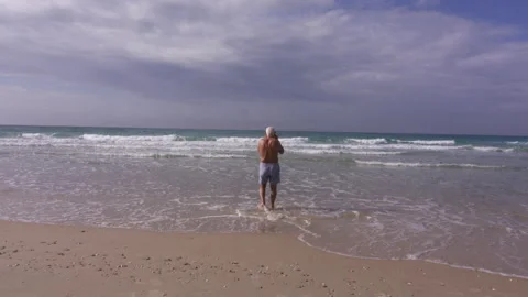 Senior man is going to swim in the ocean Stock Footage 229695232