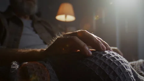 Senior man with grey beard sits alone with hand tapping on knee Video stock 315373000