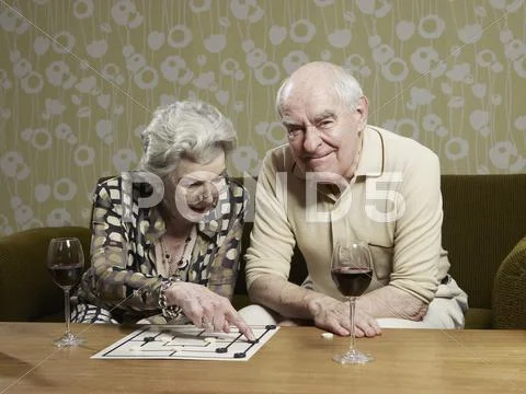 Senior man grimaces as senior woman contemplates a move playing muehle Stock Photos