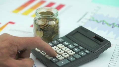 Senior man hand counts on black calculator at coins in jar Stock-Footage 134997701