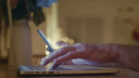 Senior man hands using smartphone and laptop computer at night Stock Footage 346414217