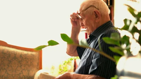 Senior man has problems with vision while reading newspaper on sofa at home Stock Footage 100160415