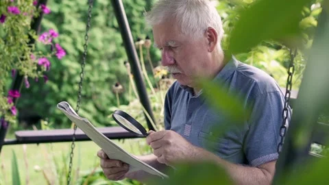 Senior man has problems with vision while reading newspaper on the swing in the Stock Footage 169165818
