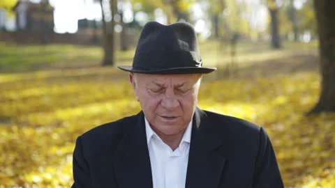 Senior man in hat takes the call and has fun talks on the mobile phone on bench Stock-Footage 133204599
