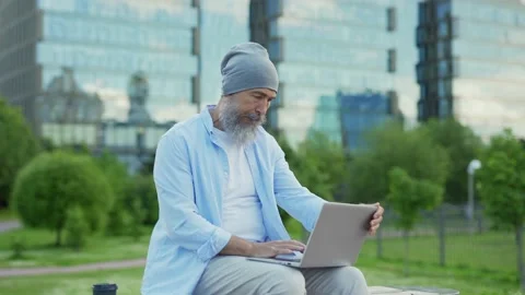 Senior man in hat using laptop and thinking outdoors Stock Footage 135463112