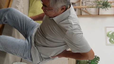 Senior man having back pain and walking by sofa Stock Footage 229620521