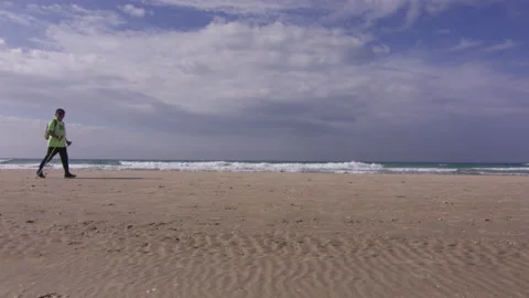 Senior man is having nordic walking on the beach along the ocean Stock Footage 229696236