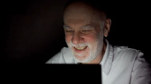 Senior man having video chat via messenger app call on laptop at night. Dark Stock Footage 89940306