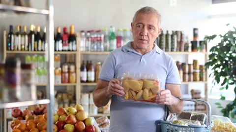 Senior man holding plastic containers with poultry half chicken carcass, choose Stock Footage 344776925