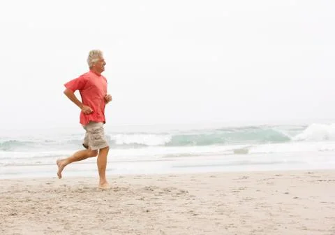 Senior Man On Holiday Running Along Winter Beach Stock Photos
