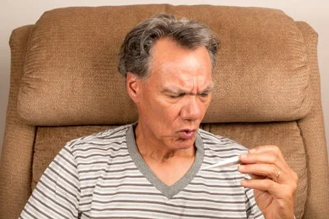 Senior Man at home checking his Temperature Stock Photos